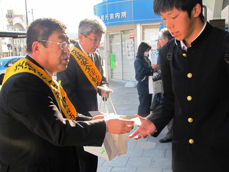 宮古駅前で市長と関係者が襷をかけて、学生に啓発チラシを手渡す写真