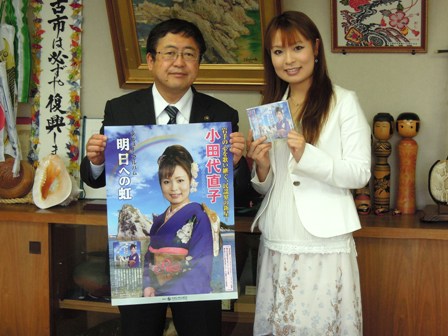 「明日への虹」と書かれた着物姿の小田代直子さんが映るポスターを手に持つ市長と、CDを両手に持っている小田代直子さんの写真
