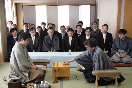 銀屏風の前に、市長と関係者が座っておりその前で、羽生善治三冠と森内俊之名人の将棋の対局が行われている写真