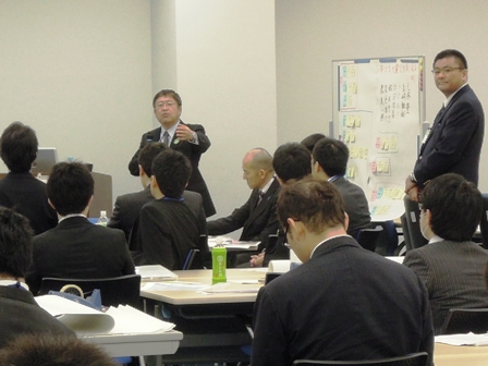 長机の席に座っている防災担当職員に向けて、市長がマイクを持ち話をしている様子の写真