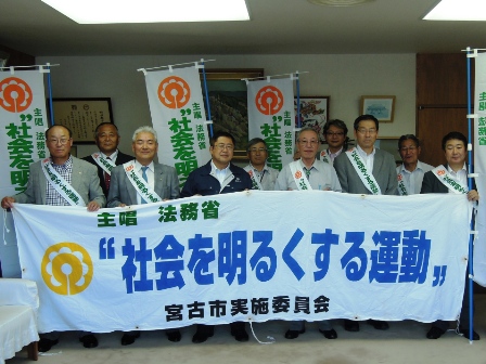 「主唱法務省”社会を明るくする運動”宮古市実施委員会」と書かれた横断幕とのぼり旗を持った複数の男性が並んで記念撮影している写真