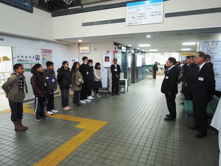 横一列に並ぶ子供たちと、向かい側に立つ市長、関係者の方々の写真