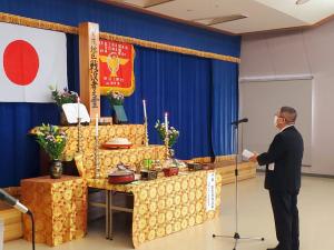 祭壇に向かってスタンドマイクの前で話をする様子の市長の写真