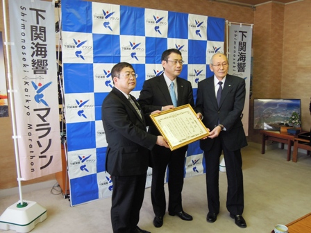 バックパネルの前で市長と中尾下関市長、丸山委員長が3人並んでいる写真