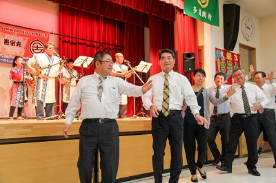 市長と関係者が、ステージの下で輪踊りをしている写真