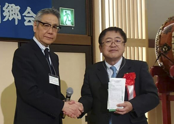 支援金を手に持つ市長と白戸会長が握手をしている写真