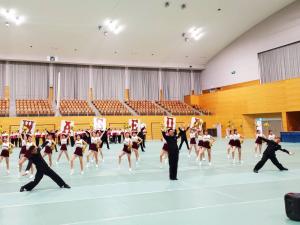 体育館のフロアで応援部の学生たちが演技をしている様子の写真
