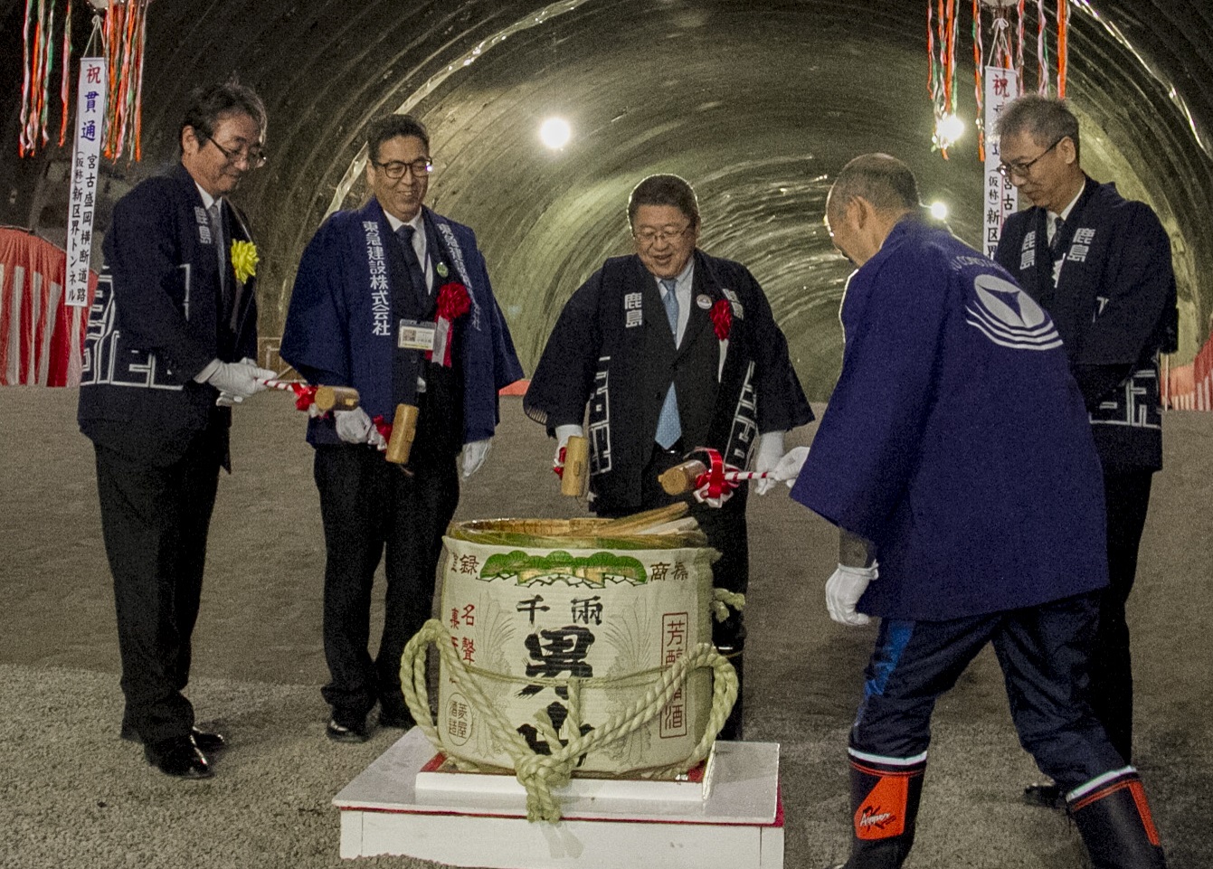 トンネル内で半被をきた市長と4名の関係者が酒樽を割っている写真