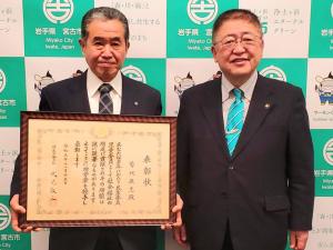 宮古市のバックパネルをバックに賞状を持って笑顔の菊地辰志様と市長が並んで記念撮影をしている写真