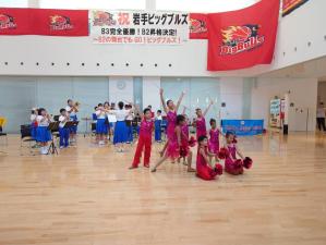 大きなホールで後方で演奏、前方でバトントワリングの演技を披露している大阪ジュニアバンドの子供たちの写真