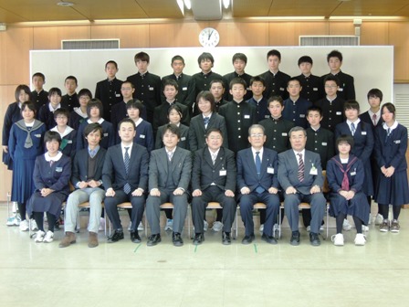 市役所庁舎で、市長と関係者、制服姿の学生の皆さんが横並びに4列で並んで集合している写真