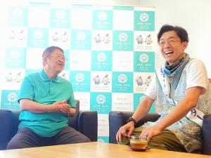 ソファーに腰掛けた市長と天津木村さんが笑顔で談笑している様子の写真