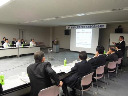 山本市長が自席で立ち、スクリーンに映し出された資料を用いて、参加者の方々に宮古市の現状を発表している写真