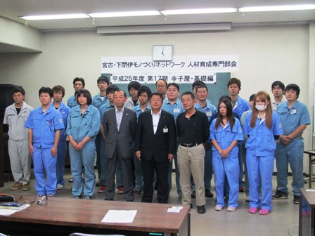 市長と、両側に立つ男性2名を中心に、作業服を着た参加者たちが3列に立って並んでいる記念写真