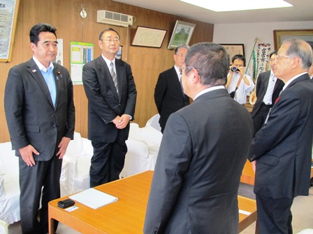 テーブルを挟んで向かい合わせに立つ市長と関係者の方々の写真