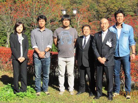 市長を含むスーツ姿の男女3名と東京ヤクルトスワローズの選手3名が紅葉した木々の前で記念撮影をしている写真