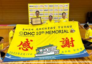 高田延彦さん、市長、向井亜紀さんの前に、高田式体育教室DKC（ダイヤモンドキッズカレッジ）の宮古市での10回目の開催を記念した「感謝」と書かれた大漁旗が広げられている写真