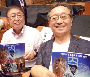 観客席に座った市長と男性が演奏会のポスターを笑顔で持っている写真