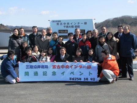 「三陸沿岸道路 宮古中央インター線 開通記念イベント」の横断幕を市長や参加者が手に持ち、3列で横並びに集合している写真