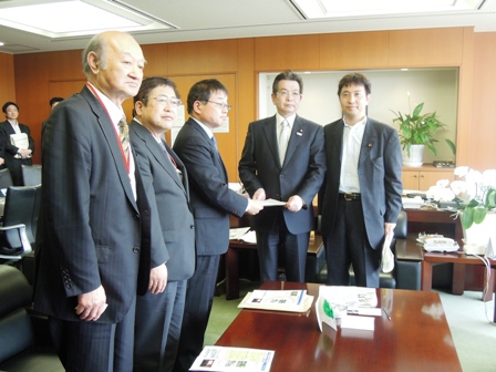 応接室のような部屋で、市長と関係者が並んでおり、書面を手渡している写真