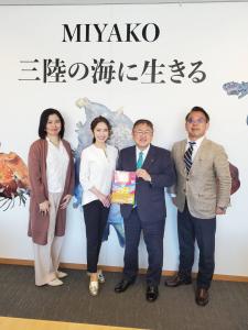 「MIYAKO 三陸の海に生きる」という文字と魚の絵が描かれた壁の前で記念撮影をする市長と女性2名、男性1名の写真