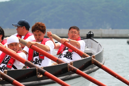 ボートに乗り、選手たちと一緒にオールを漕ぐ市長の写真
