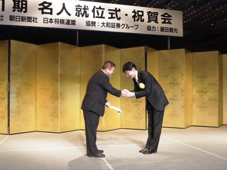 金屏風の前で、谷川浩司日本将棋連盟会長から義援金を受け取る市長