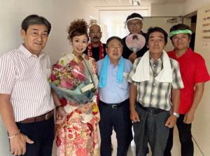 花柄の着物を着て花束を持った小田代直子さんとどっこい隊「宮古市海の男達」の男性ら7名の集合写真