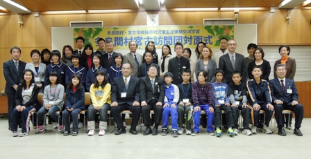 多良間村宮古訪問団対面式と書かれた横断幕の下で1列目に13人が椅子に座り2列目名が12名が立ち3列目に10名4列目に2名が並んだ集合写真