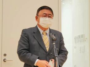 「宮古のクリスマスコンサート・イルミネーション点灯式」の会場の大きな白い扉の前に設置されたマイクスタンドの前で挨拶を行っている市長の写真