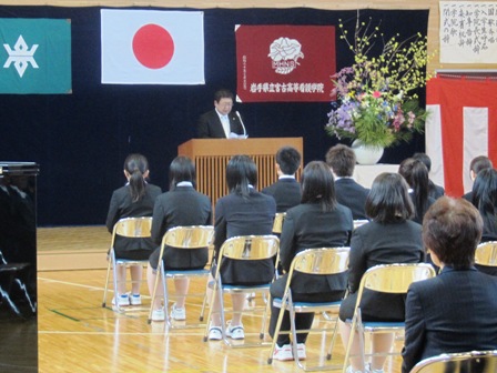 紅白幕が壁に張られ、椅子に座る新入生の前で演壇に立ち話をする市長の写真