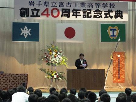 「岩手県立宮古工業高等学校 創立40周年記念式典」と書かれた横断幕、日本国旗や校旗が掲げられた舞台上で、演台のマイクに向かい話をする市長の写真
