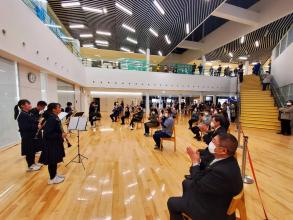 イーストピアみやこ市民交流センターの広場で、演奏が終了しクラリネットを持った中学生に向けて椅子に座った観客や市長が拍手を行っている様子の写真