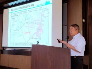 スクリーンに地図を投影し壇上で話をする市長の写真