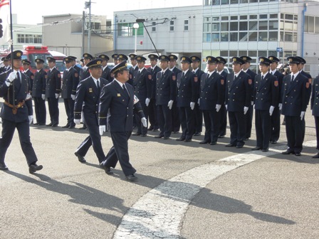 2列に並んだ消防の制服を着た職員たちの前を同じ制服を着た市長が歩いている出初式の写真