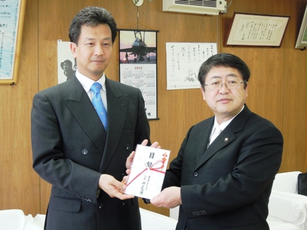 スーツに青いネクタイの井上篤博社長と市長が金封を一緒に持ち記念撮影している写真