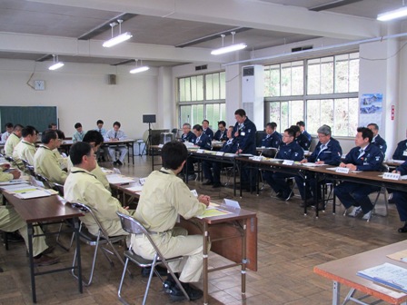 ロの字型に並べられた机に着席する関係者と、起立し話をする市長の写真