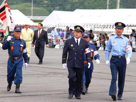 大演習が行われている会場を歩く制服姿の市長と関係者が歩いている写真