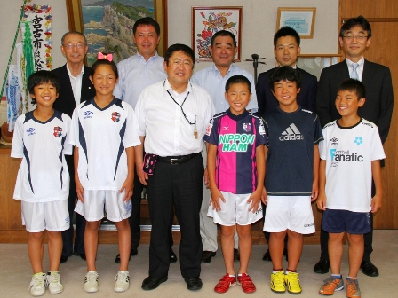 市長とサッカーのユニフォームを着た小学生くらいの子供達と関係者が2列に並んでいる写真