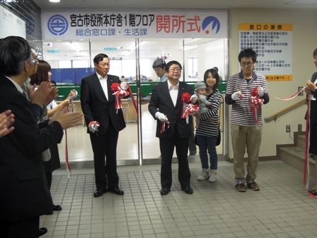 「宮古市役所本庁舎の1階フロア開所式」と書かれた横断幕が入口の上にはられ、入口の前に関係者がテープカットをしている写真
