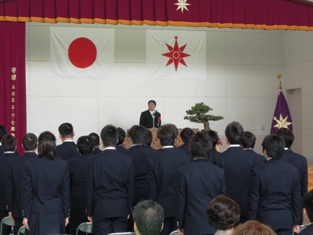 国旗と国立宮古海上技術短期大学校校旗があるステージで市長が話しているのをステージ下で生徒達がたち話を聞いている写真
