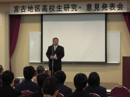 「宮古地区高校生研究・意見発表会」の吊り看板があり、舞台中央でマイクスタンドの前に立つ市長と、椅子に座り話を聞く参加者の写真