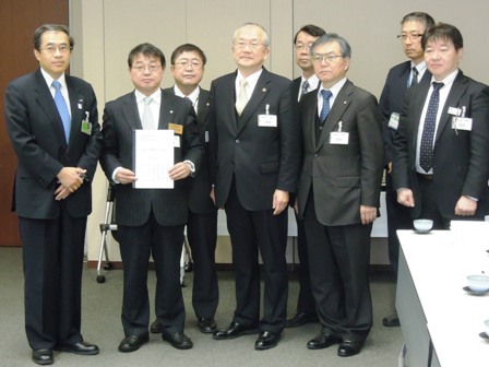 市長と関係者が横に並んでおり、深澤祐二代表取締役副社長が要望書を手に持っている写真