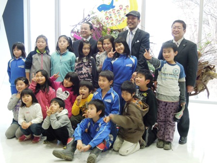 震災ガレキで作られたモニュメント前で、市長と小学生の皆さん、関係者達が、横に4列に並び集合している写真