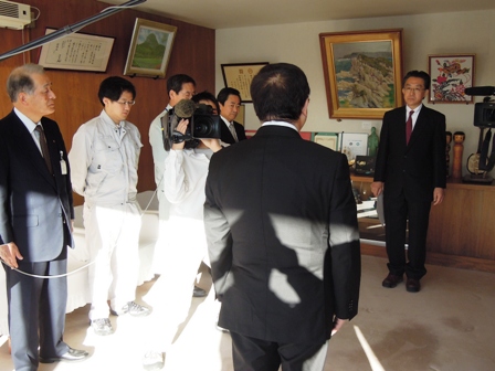 市長と橋本祥弘医師が向かい合わせに立ち着任の様子をテレビカメラで撮影している写真