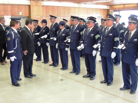 手帳を片手に持ち横並びに並ぶ警官達の前を市長が確認している写真