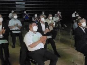 席に座っている沢山の参加者と一緒に市長が拍手をしている写真