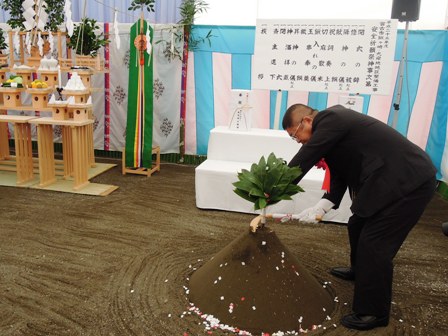 盛砂の前で鍬を持って土を掘り、整備工事の安全祈願をする市長の写真