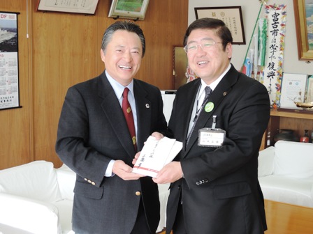 寄附金の封筒を一緒に持つ市長と男性の写真