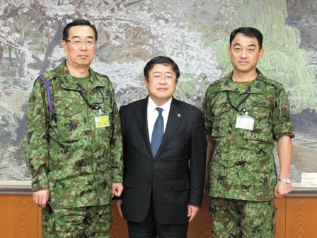 迷彩服を着た2名の男性の間に市長が立つ記念写真